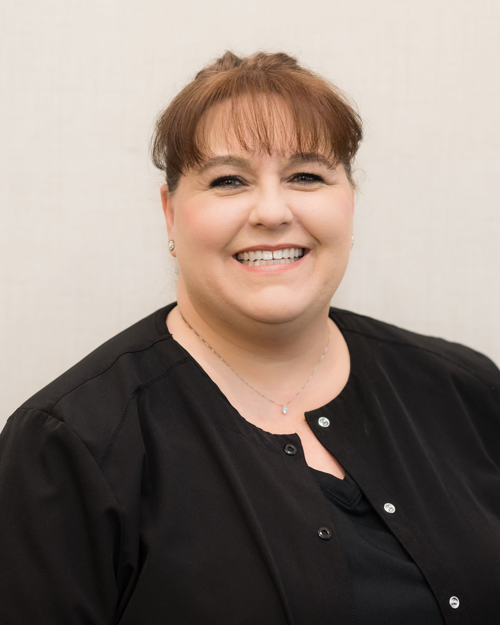 Smiling person in a black top against a light background