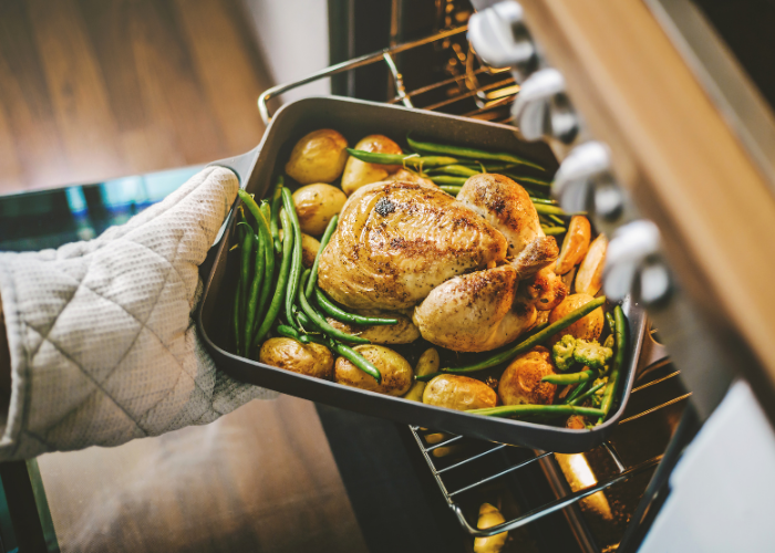person placing tray of food into oven