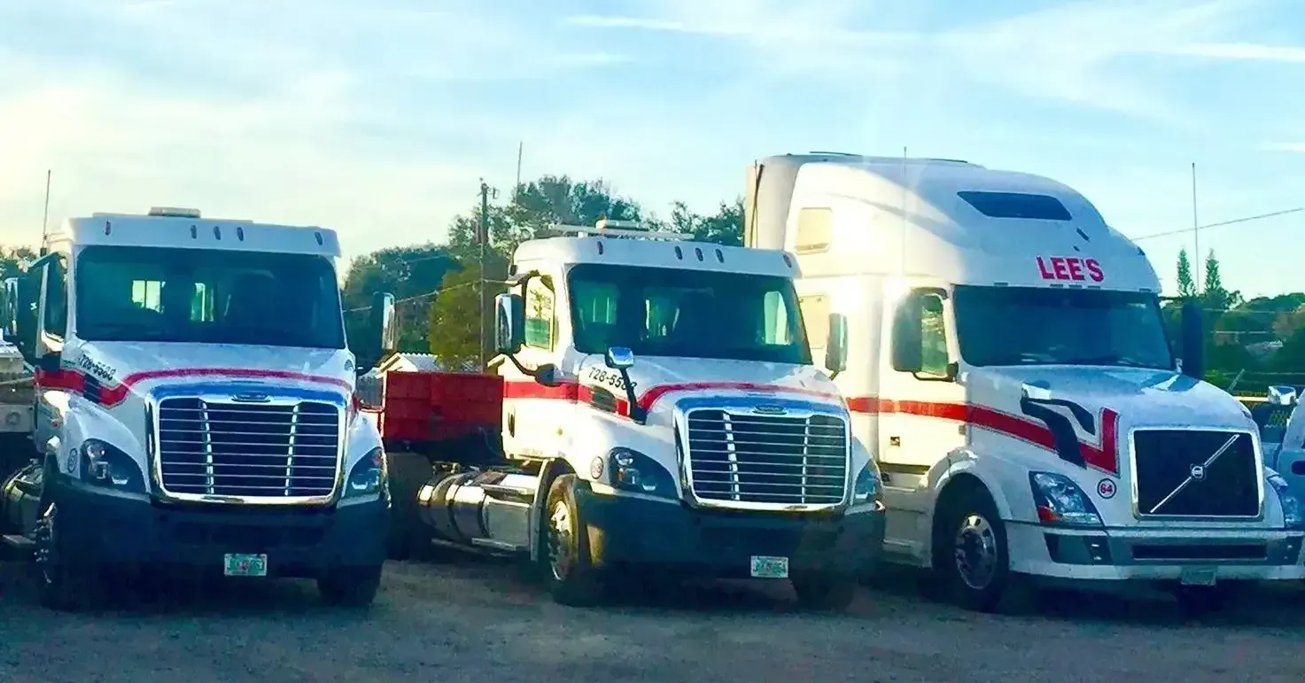 Three semi trucks are parked next to each other in a parking lot.
