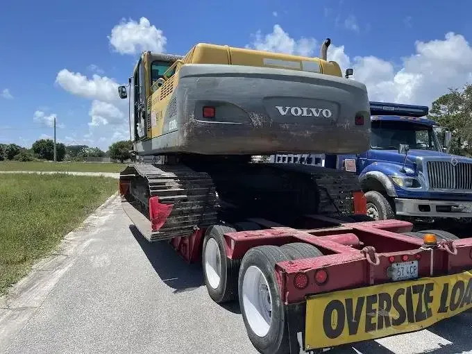 A volvo excavator is being transported on a trailer.