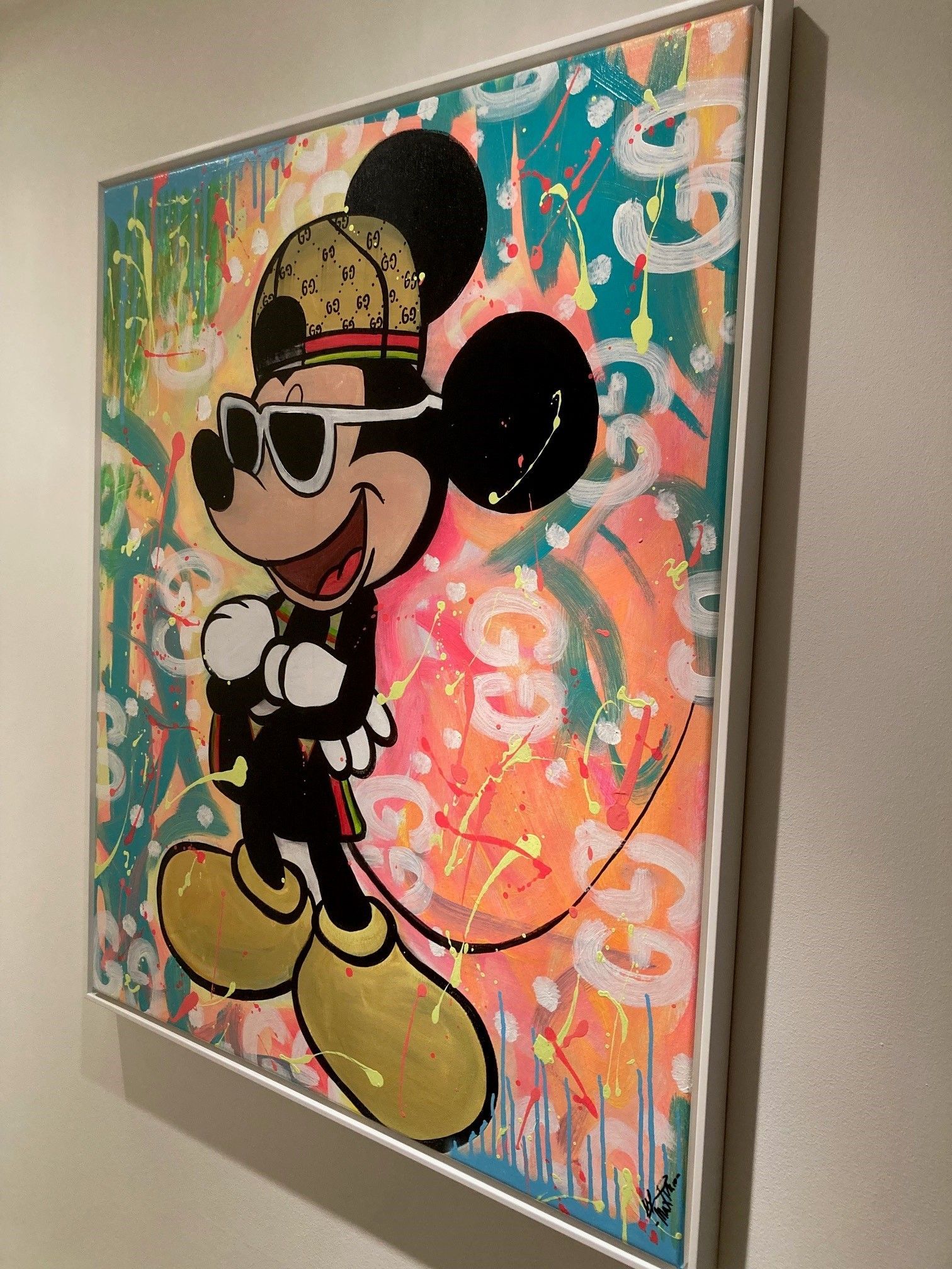 Mickey Mouse met een zonnebril en een Gucci-hoed op een kleurrijke abstracte achtergrond. Kunstwerk tentoongesteld aan een muur.