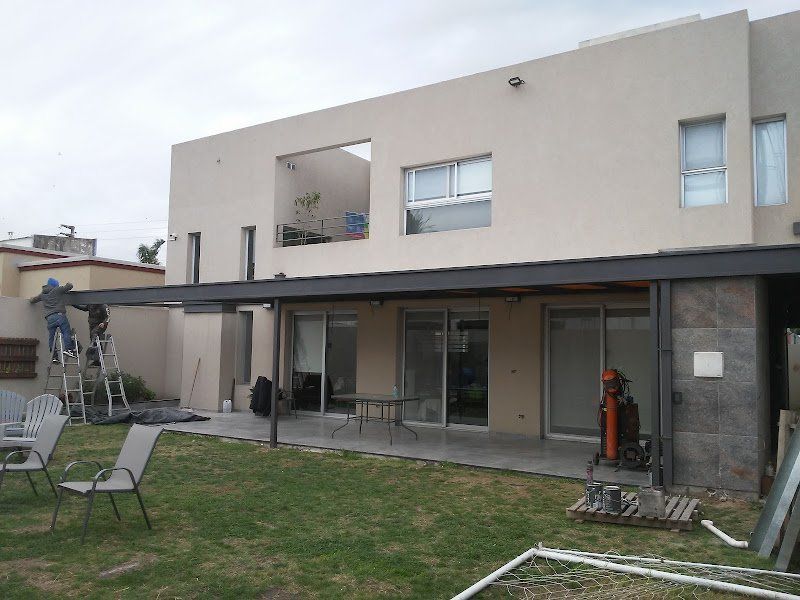 Casa moderna de dos plantas con patio cubierto y jardín, que se muestra durante su construcción o renovación.