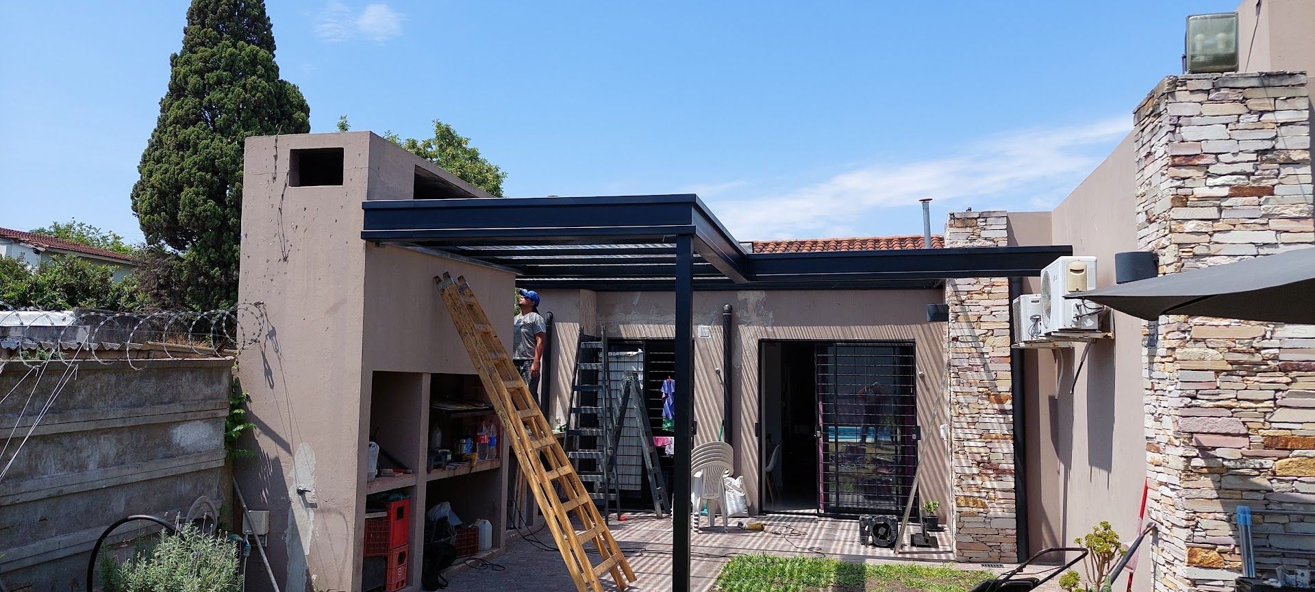 Casa parcialmente demolida con paredes de ladrillo visto, una escalera y un cielo azul de fondo.