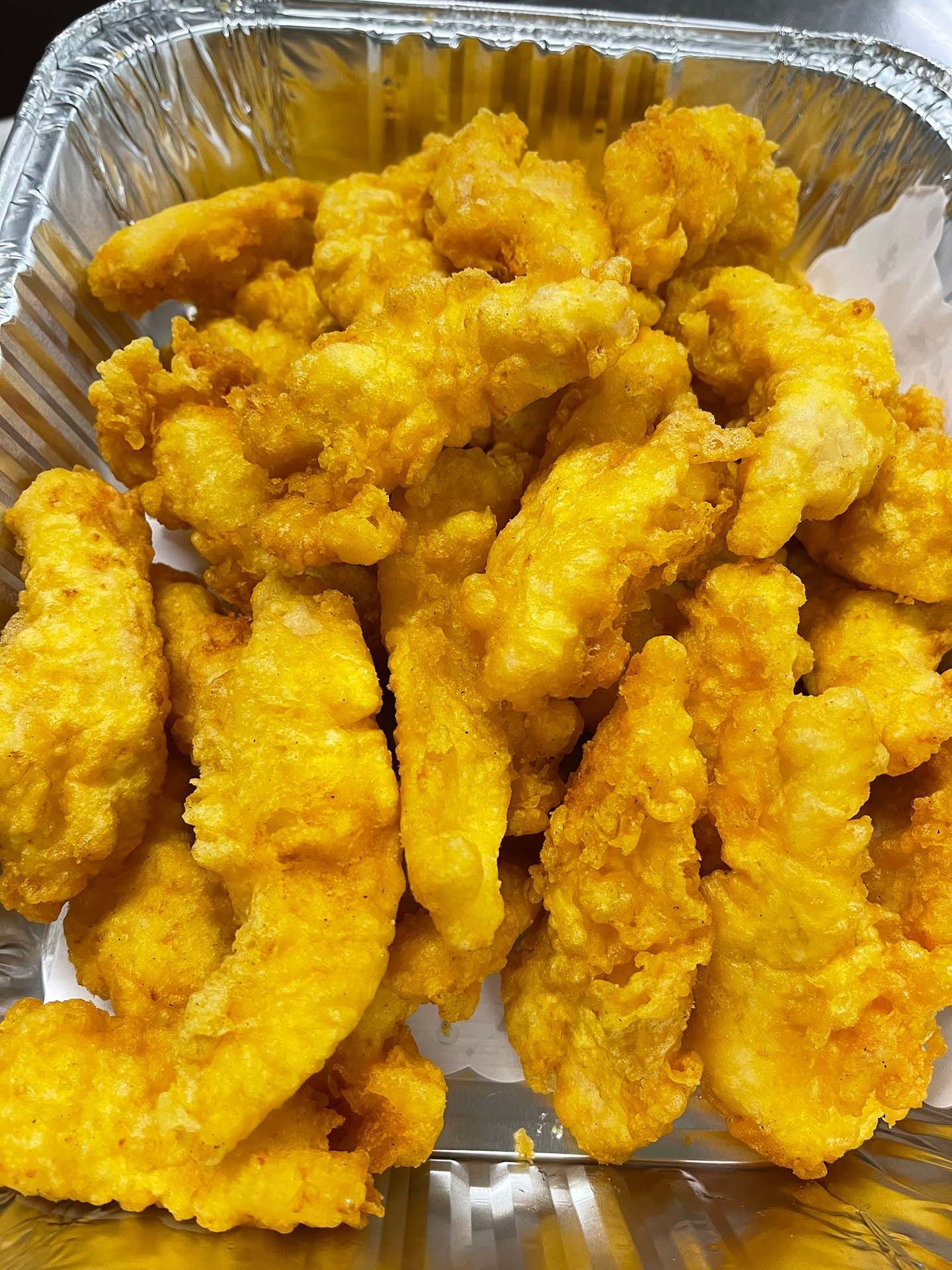 Golden fried chicken tenders in a foil container