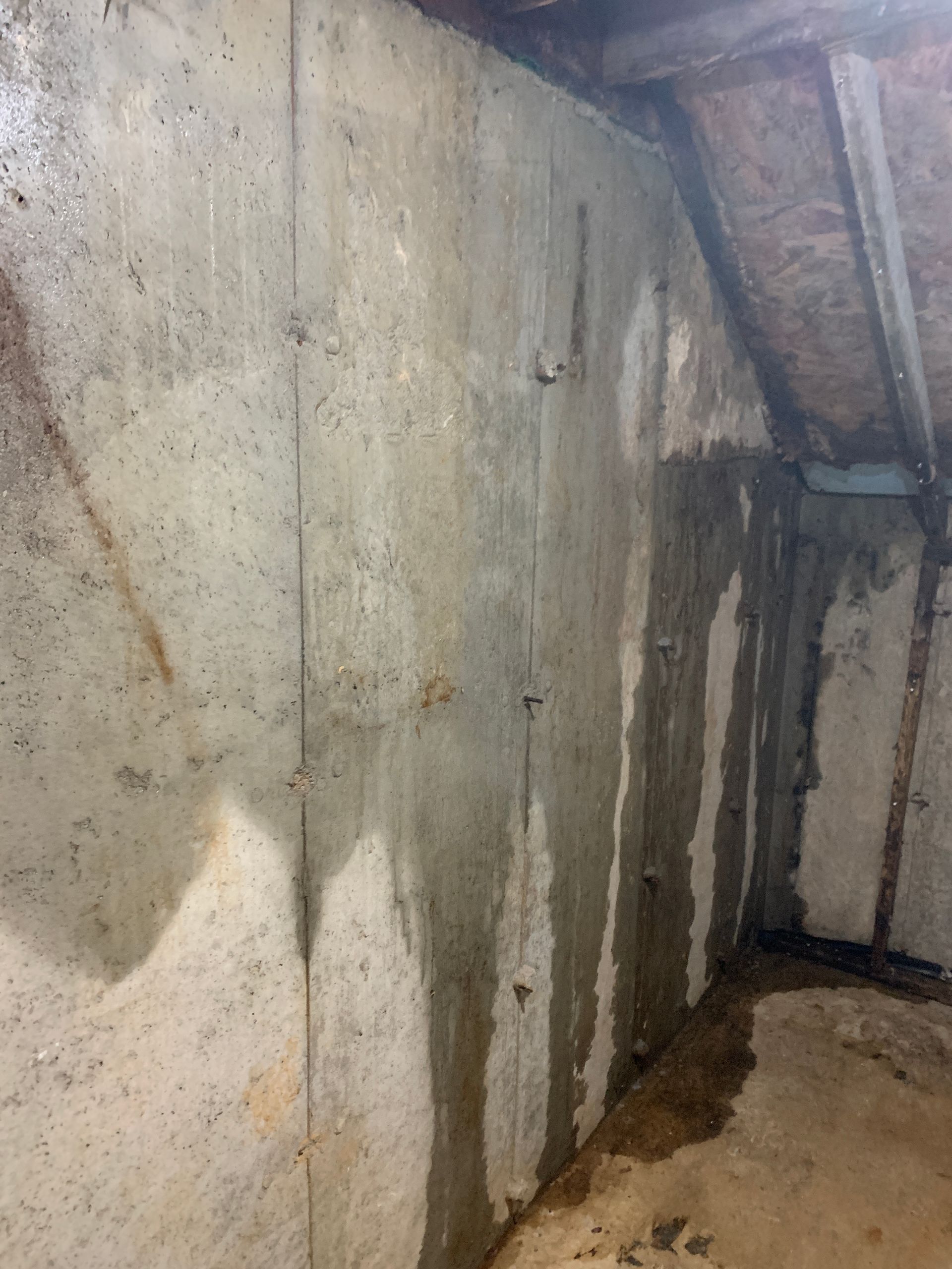 Mur de sous-sol en béton présentant des traces d'eau et d'humidité visibles, témoignant d'une infiltration d'humidité.