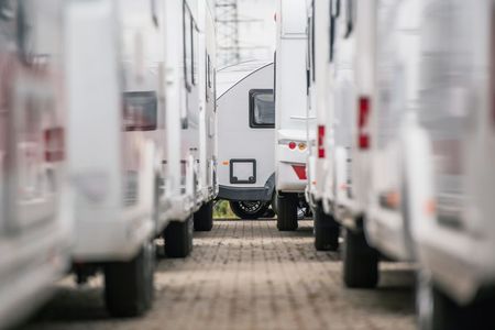 A row of rvs parked next to each other in a parking lot.