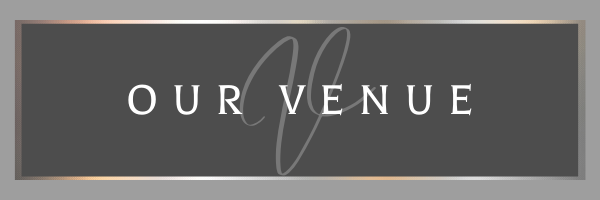 Dark gray sign with white text reading “OUR VENUE” and a thin beige border.