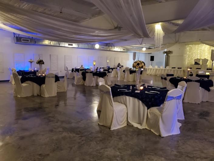 Banquet hall with round tables dressed in navy and white tablecloths under draped ceiling lights