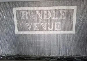 White-framed sign reading “R NDLD VENUE” on a textured gray surface.