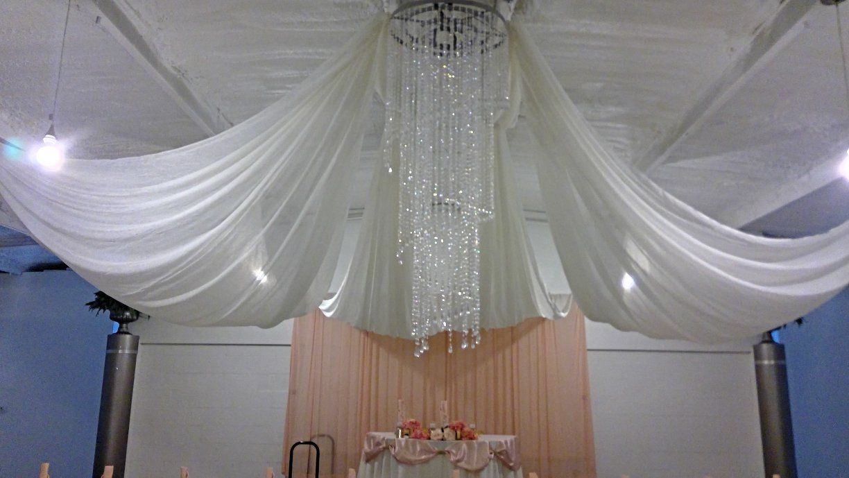 White draped ceiling with hanging crystal strands over a decorated stage area and table below