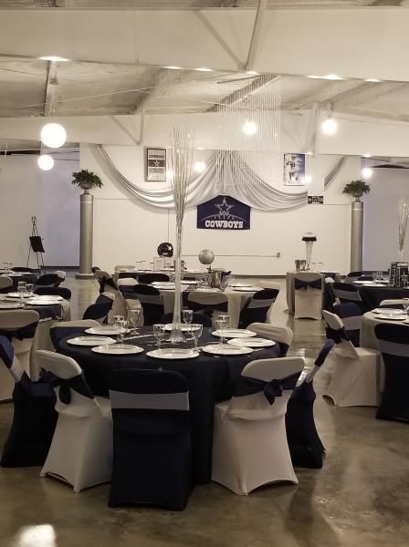 Banquet hall with round tables dressed in black-and-white linens and ceiling drapes for an event