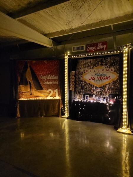 Las Vegas-themed event backdrop with red curtains, string lights, and a glossy floor under a low ceiling