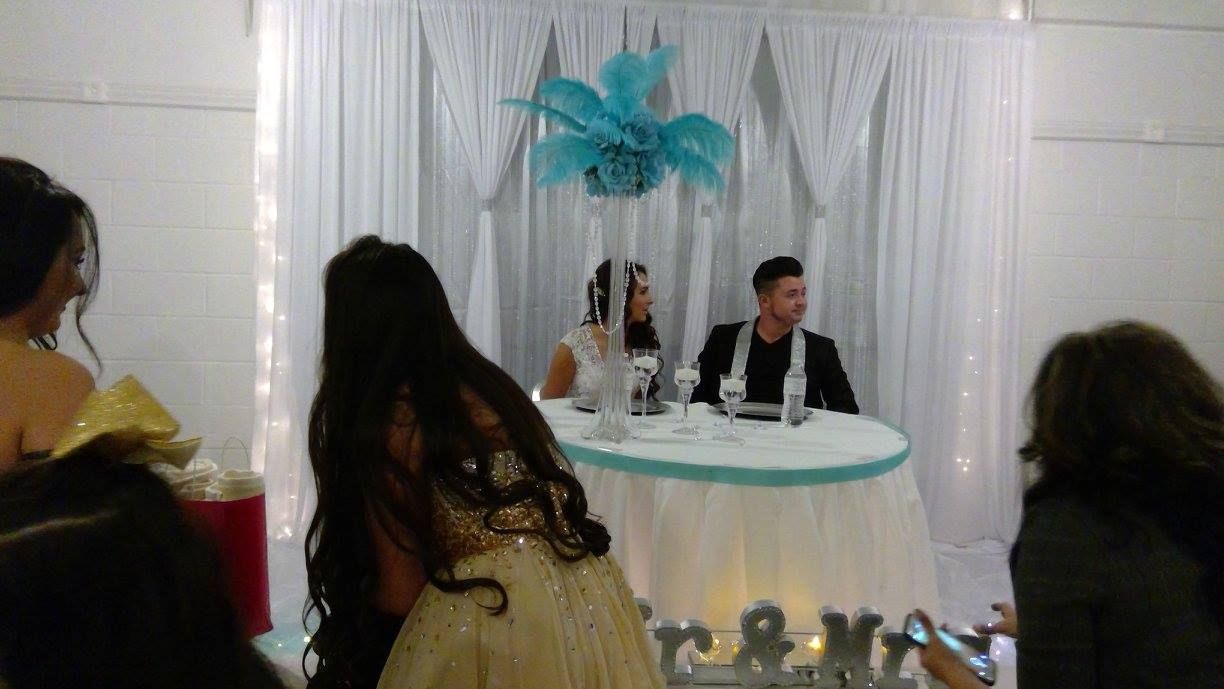 Wedding reception with bride and groom seated at a decorated white table