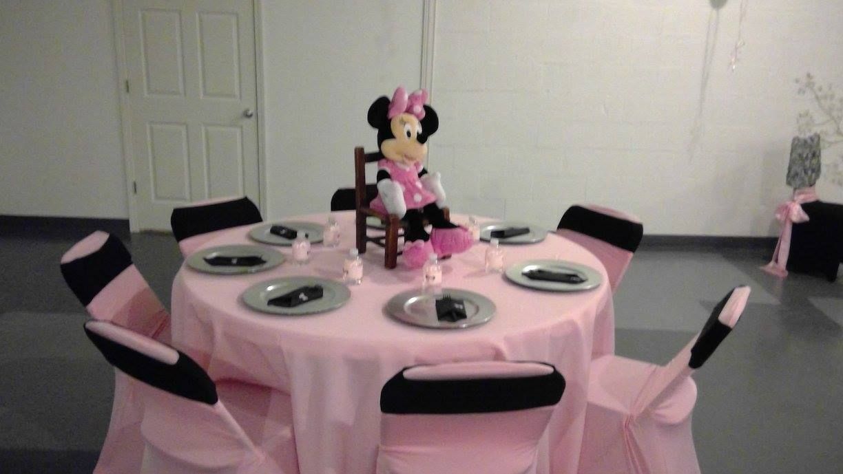 Pink Minnie Mouse birthday table with black-and-pink chairs, plates, and decorations in a room