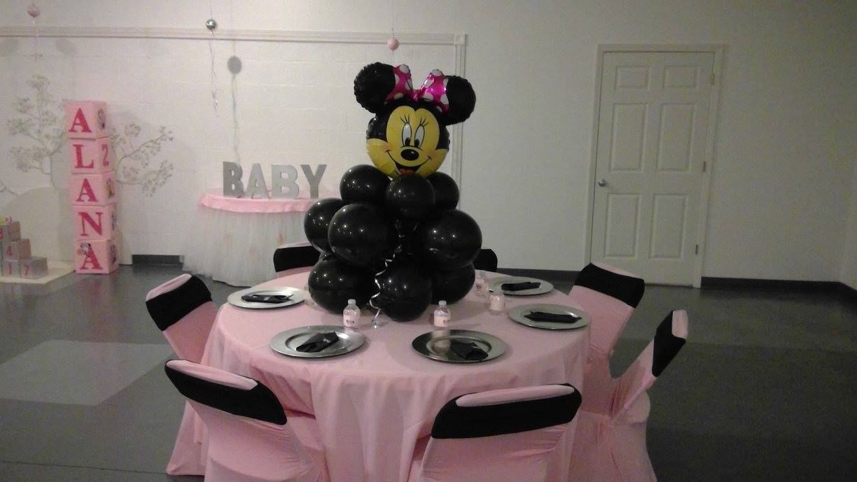 Pink baby shower table with black balloons and a Minnie Mouse centerpiece in a decorated room