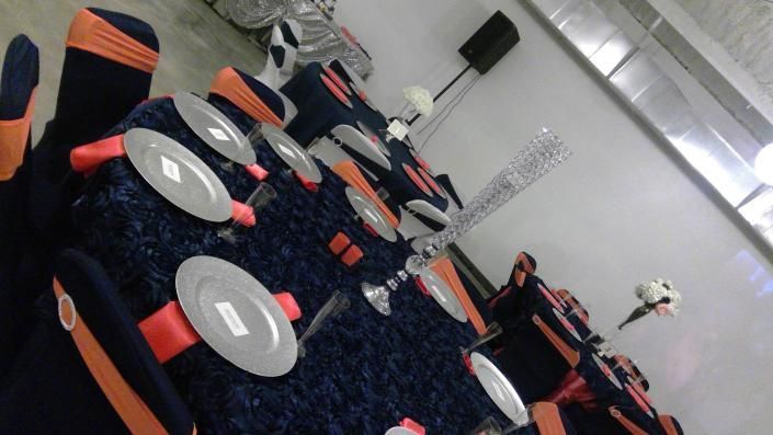 Rows of orange-and-black auditorium seats in a dim indoor hall with a person seated at the back.