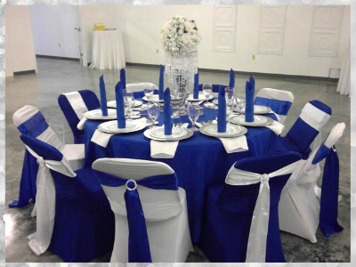 Round banquet table with royal blue and white drapes, blue candles, and white floral centerpiece in a reception hall
