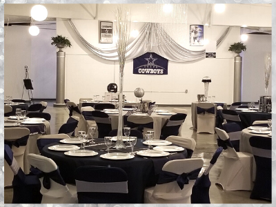 Banquet hall with round black tables, white chairs, and draped white fabric decorations