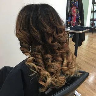A woman is sitting in a chair with her hair curled in a salon