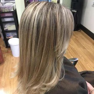 A woman with long blonde hair is sitting in a chair in a salon.