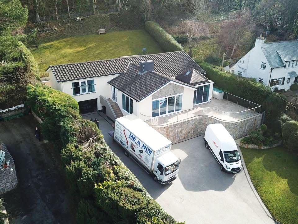 White Me & Him Removals truck and van parked outside a detached bungalow property in North Wales.