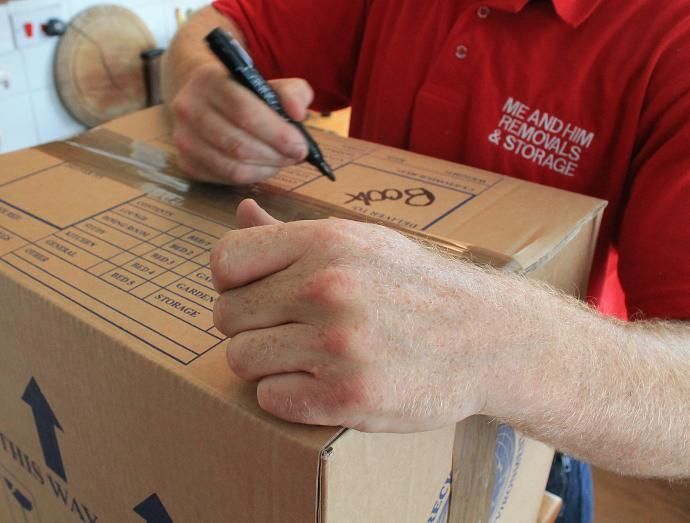 ME & HIM REMOVALS & STORAGE TEAM WRITING ON PACKING BOX