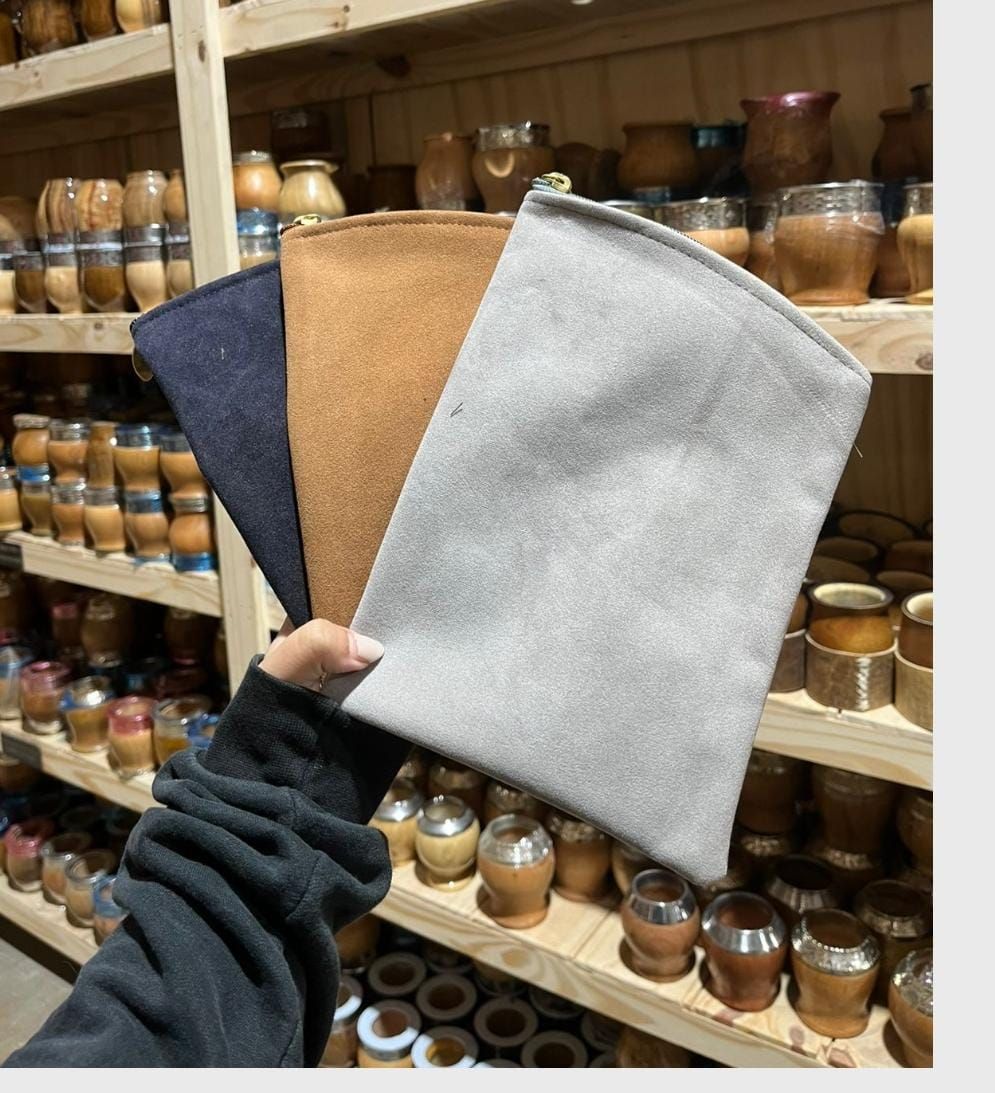 Una mano sostiene tres muestras de tela de fieltro en color tostado, azul marino y gris claro en el pasillo de una tienda.