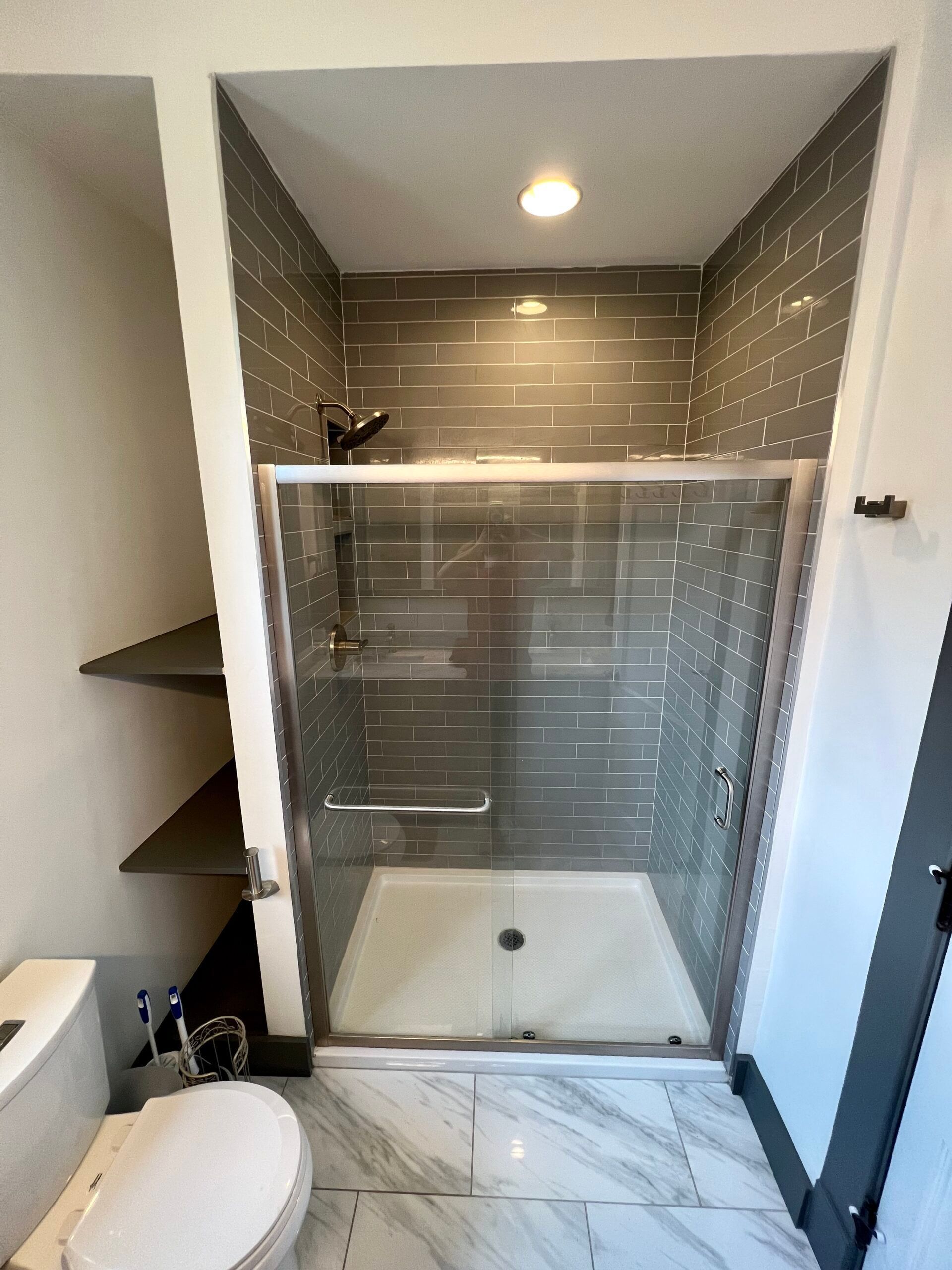 A bathroom with a toilet and a walk in shower.