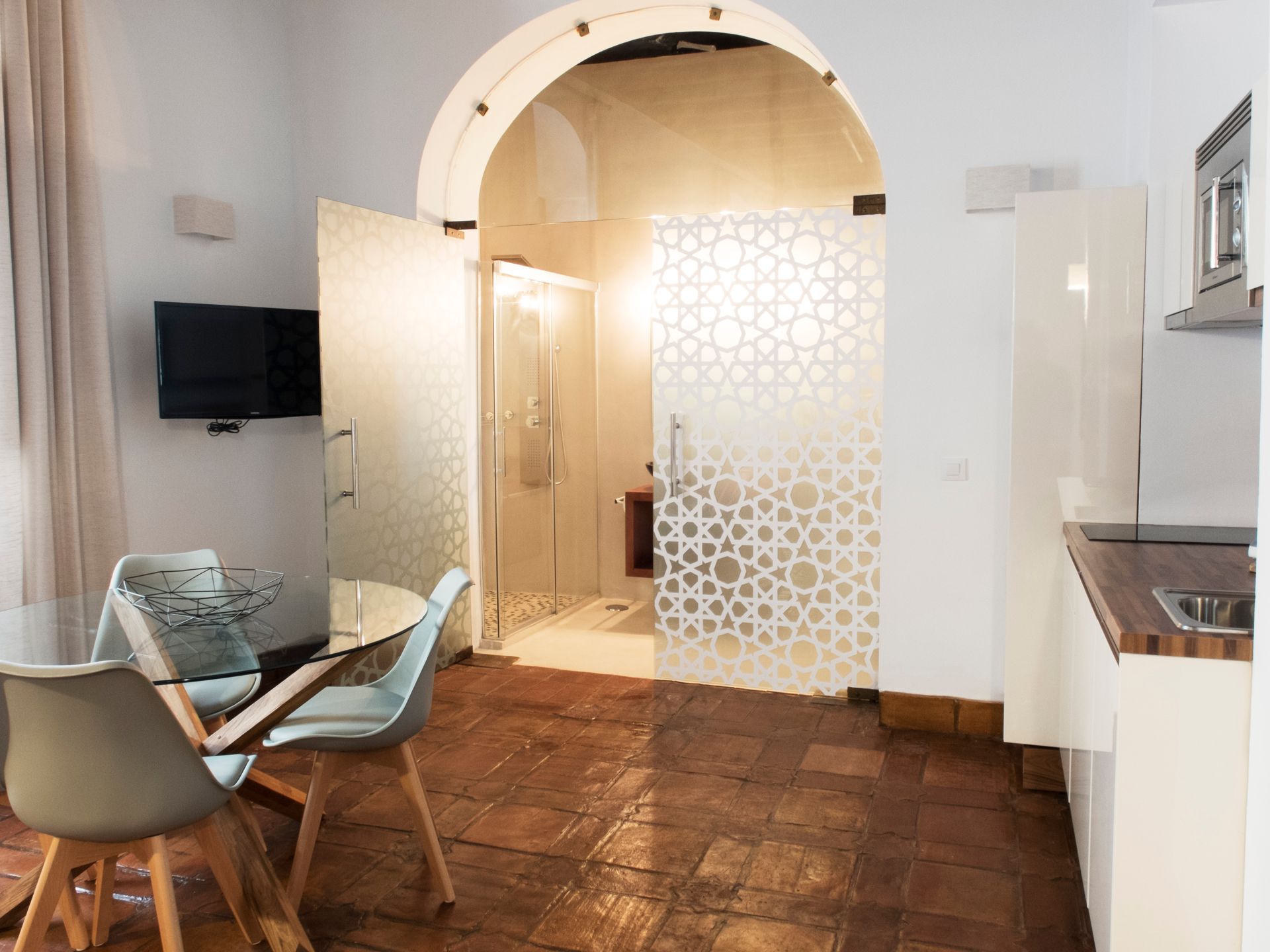 Modern kitchen-dining room with wood floor, white walls, arched doorway, and two chairs by a table