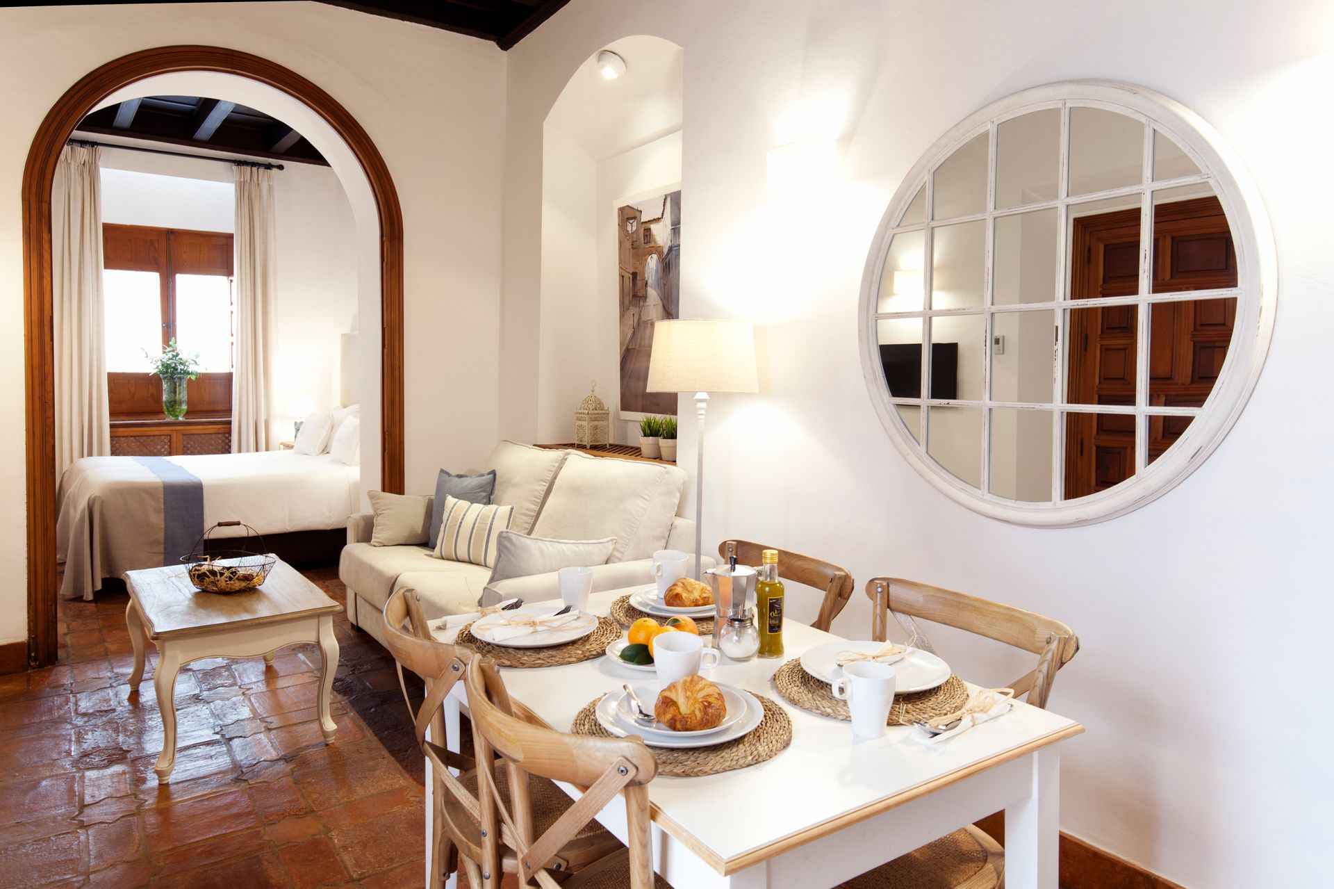 Bright dining nook with a set table, cream sofa, and arched doorway in a cozy apartment interior