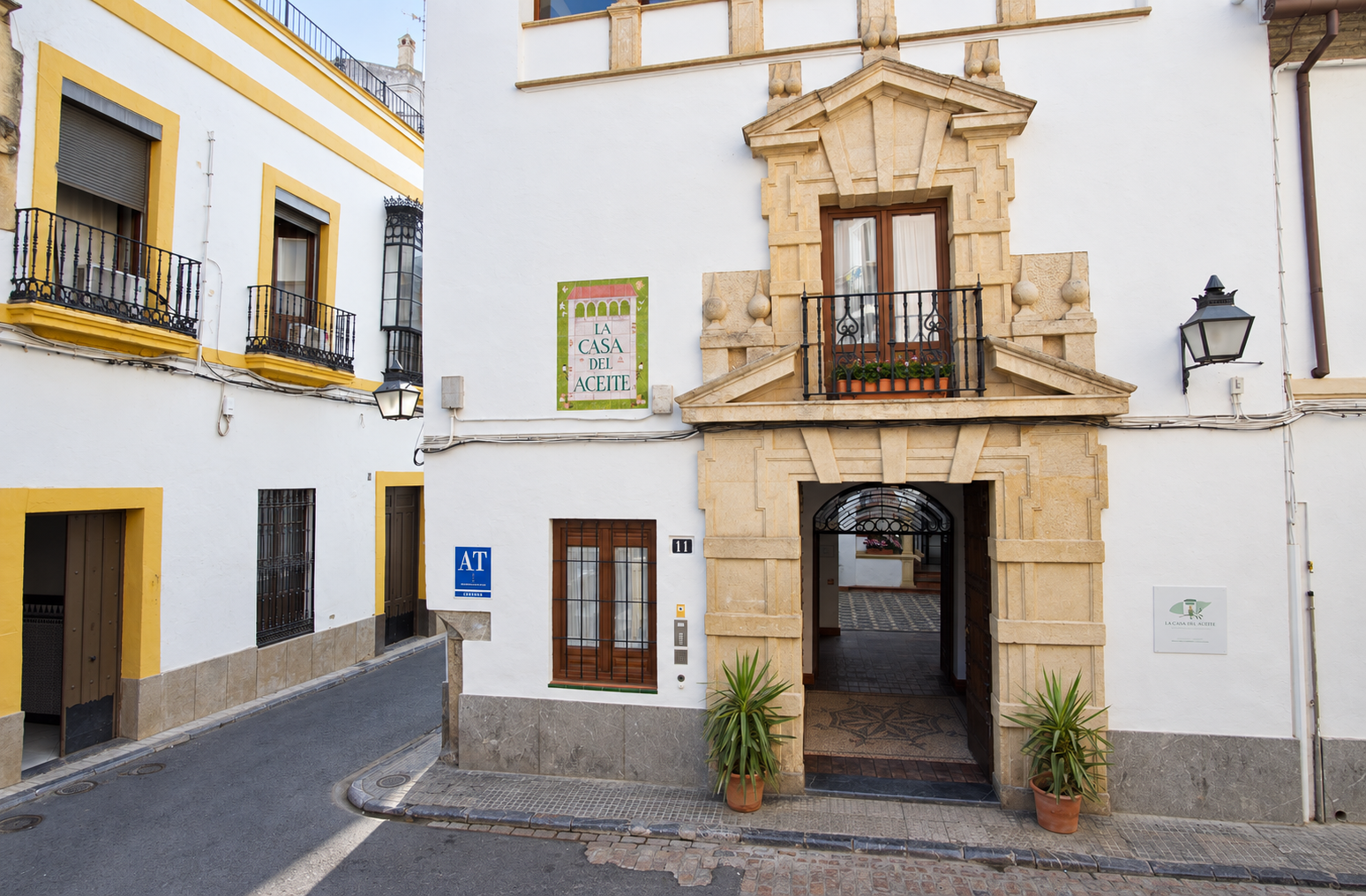 Narrow white street with yellow buildings and a stone archway entrance on a cobblestone road