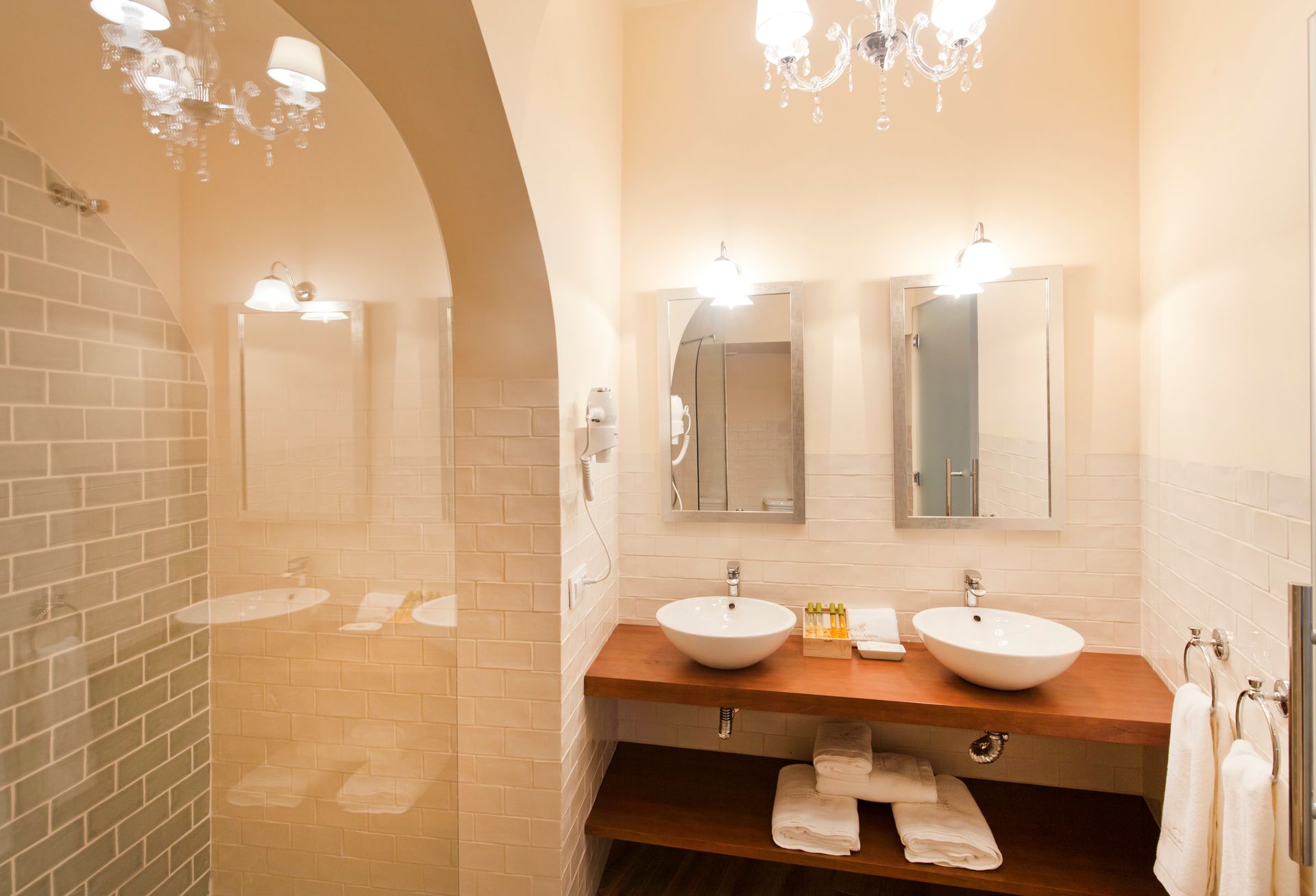 Elegant bathroom vanity with two vessel sinks, mirrors, and a glass shower enclosure