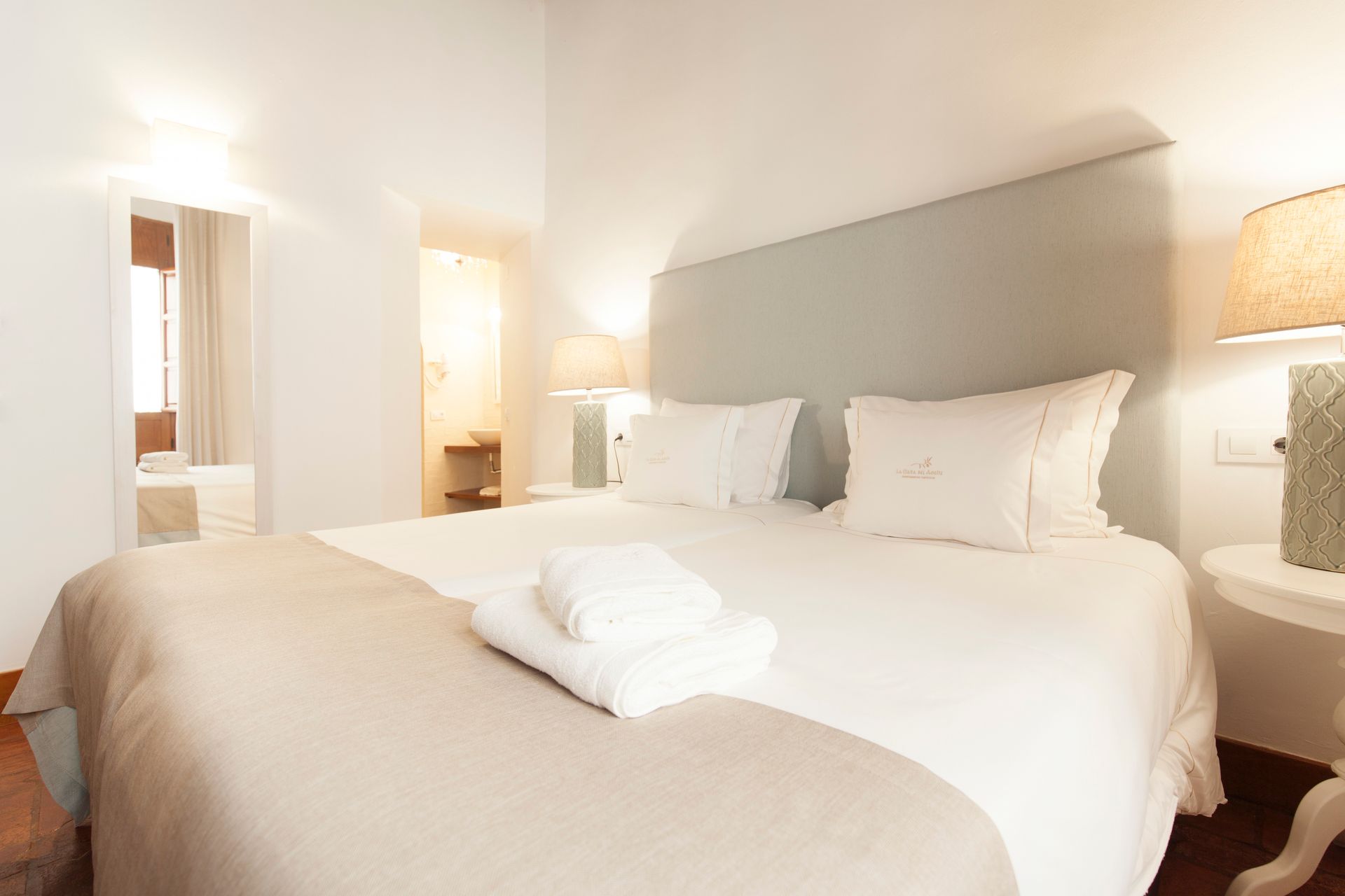 Bright bedroom with a large bed, white linens, and a bedside lamp in a minimalist interior