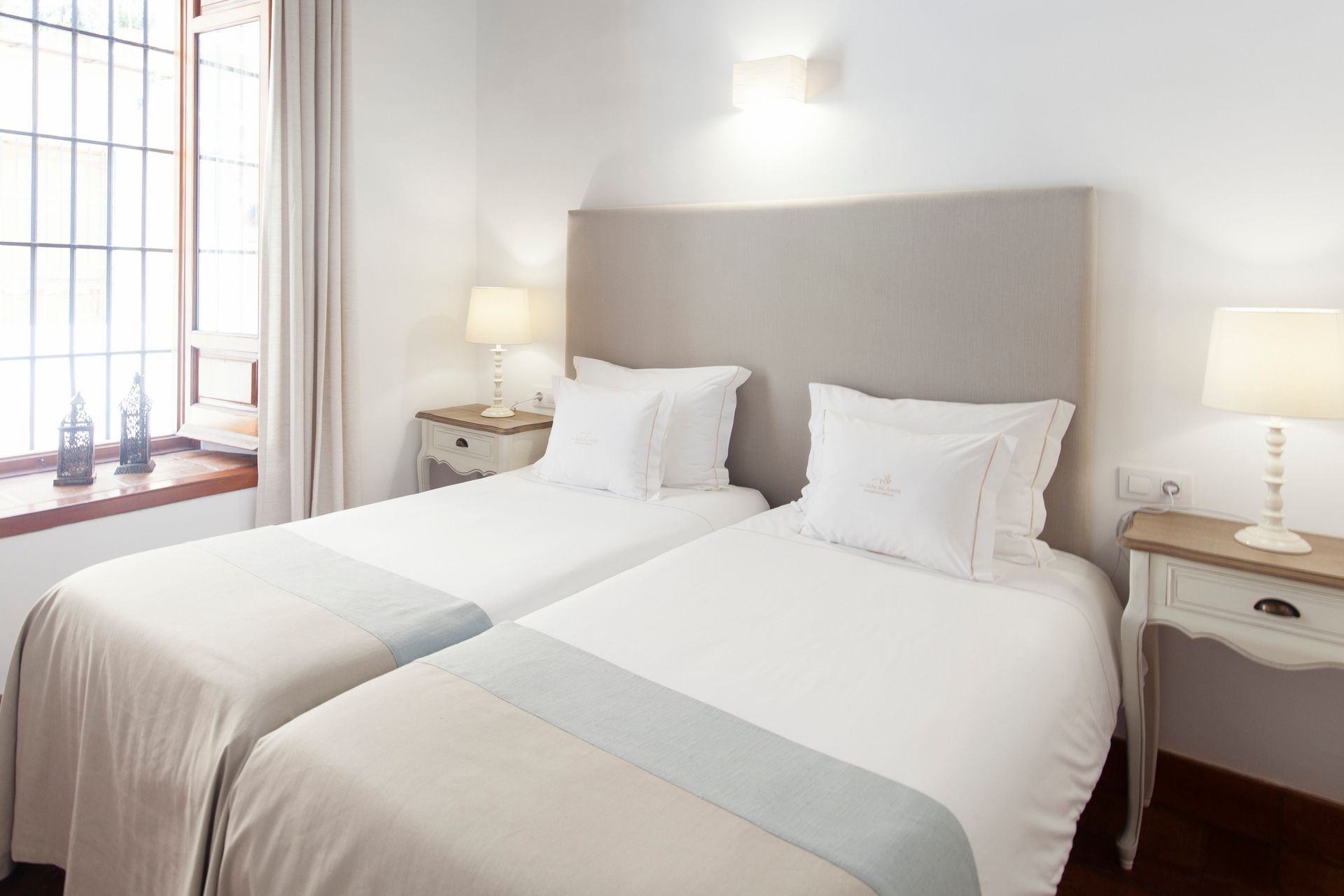 Bright hotel room with two neatly made twin beds, white bedding, and bedside lamps