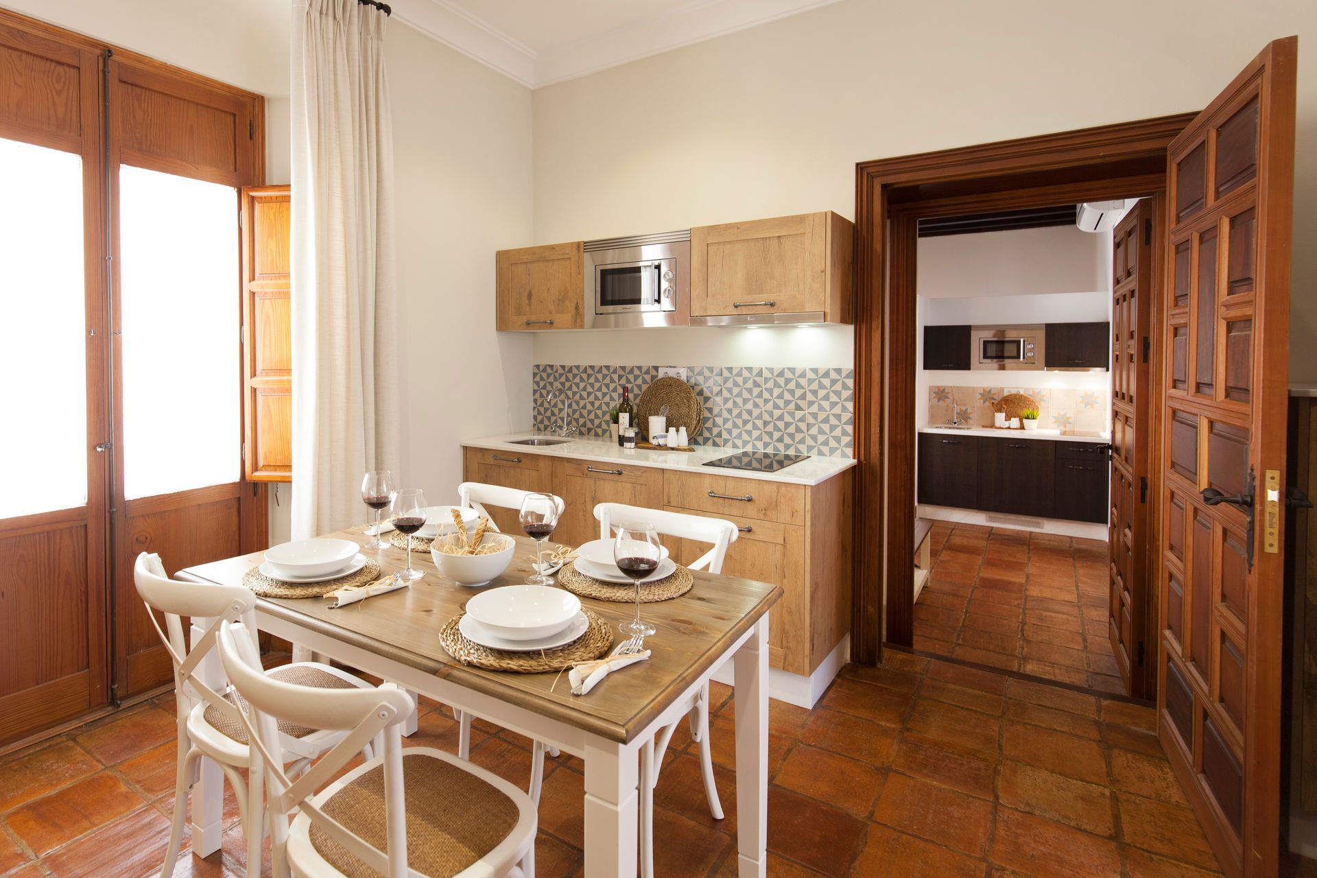 Bright kitchen-dining room with wooden table set for breakfast and cabinets