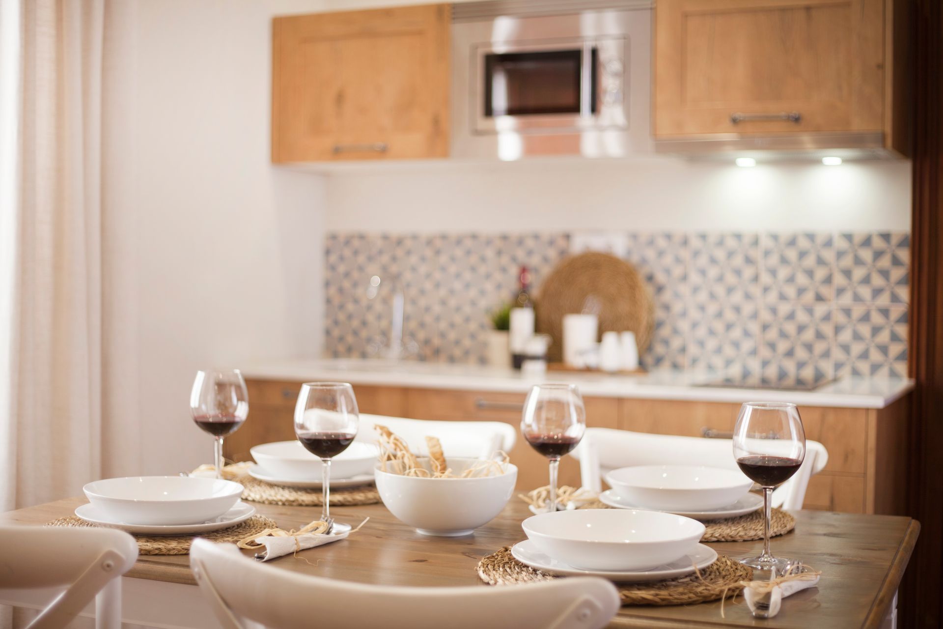 Set dining table in a modern kitchen with plates, wine glasses, and a bowl centerpiece