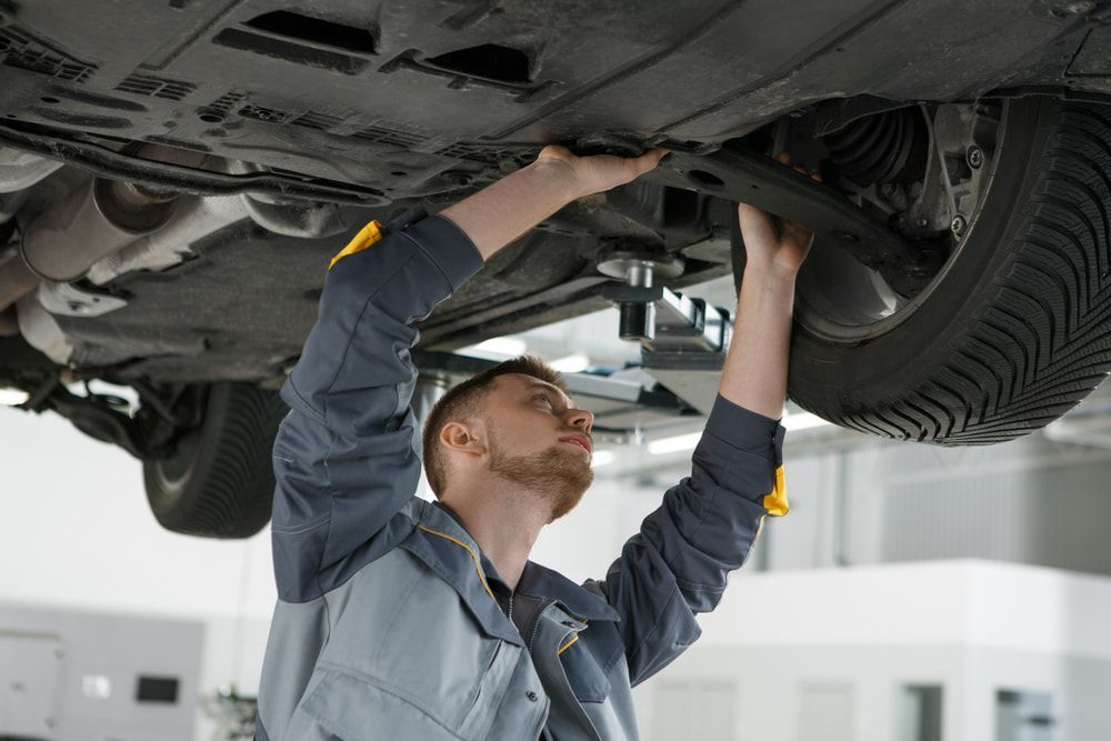 A Man Is Working Under A Car In A Garage โ Tonics Automotive in Garbutt, QLD