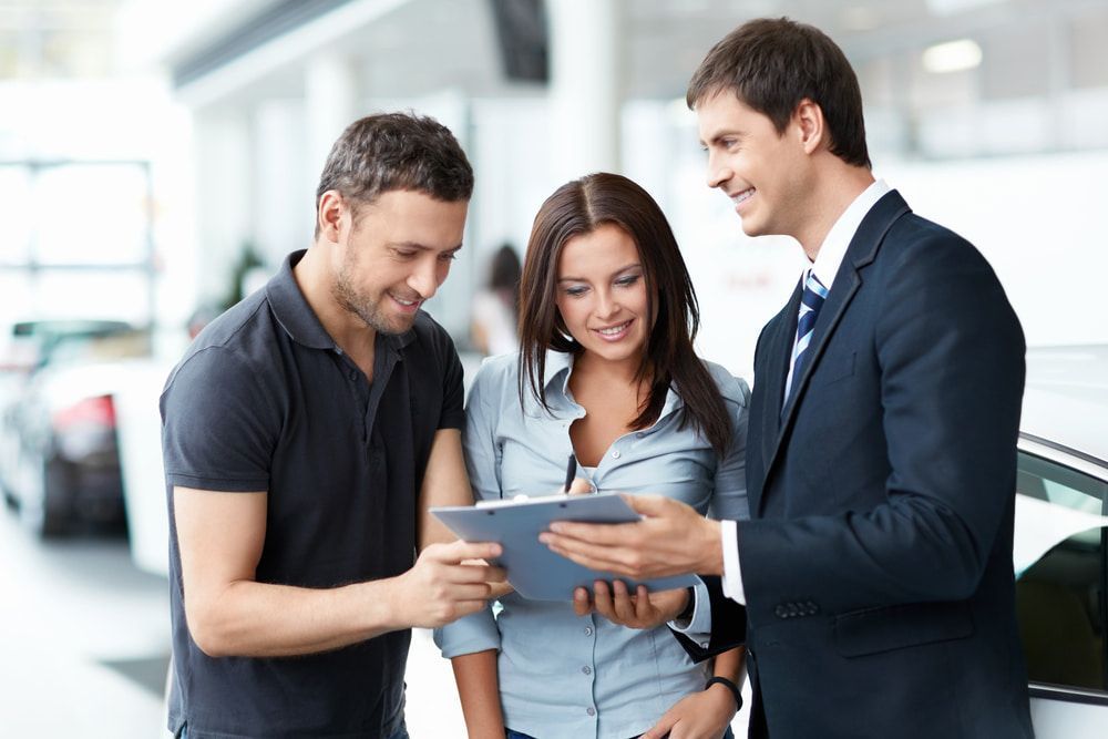 A Man And A Woman Are Looking At A Tablet In A Car Showroom โ Tonics Automotive in Garbutt, QLD
