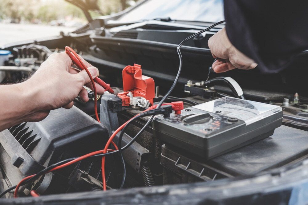 A Person Is Working On A Car Battery With A Multimeter — Tonics Automotive in Douglas, QLD