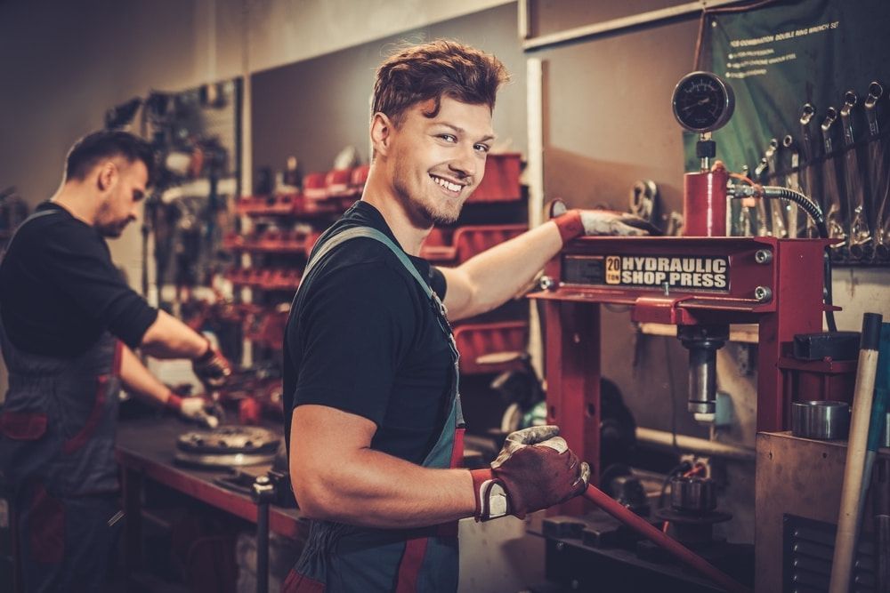 Two Men Are Working On A Machine In A Garage — Tonics Automotive in Garbutt, QLD