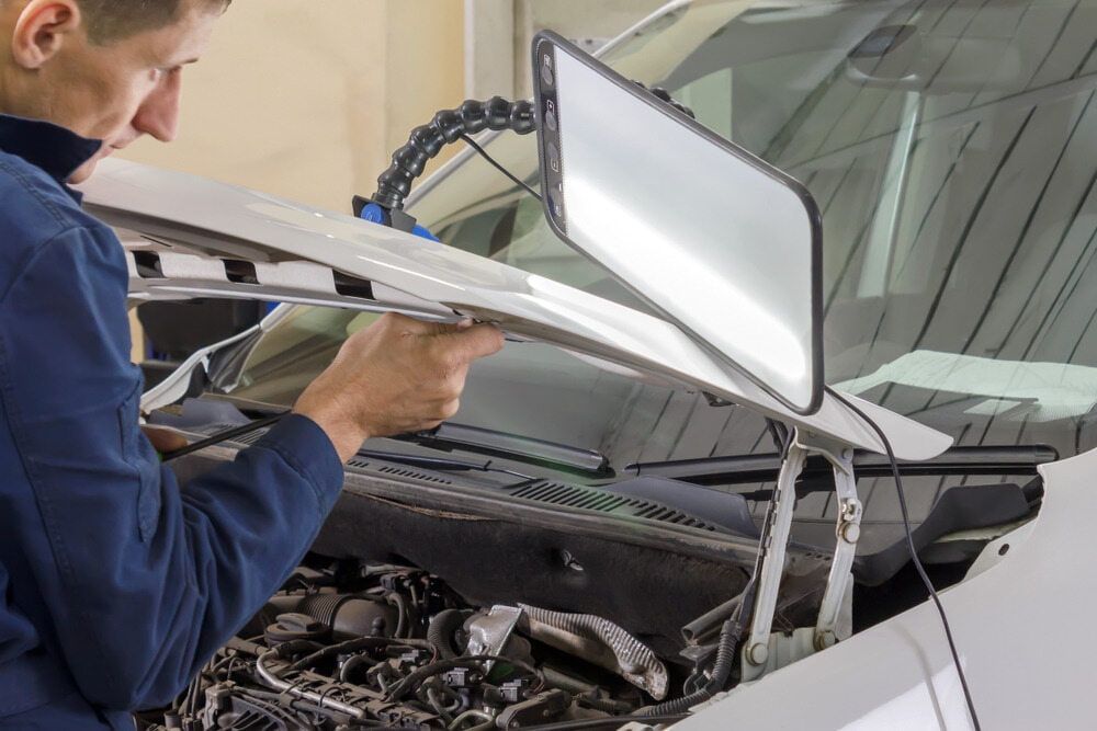 A Man Is Working On A Car With The Hood Open — Tonics Automotive in Annandale, QLD
