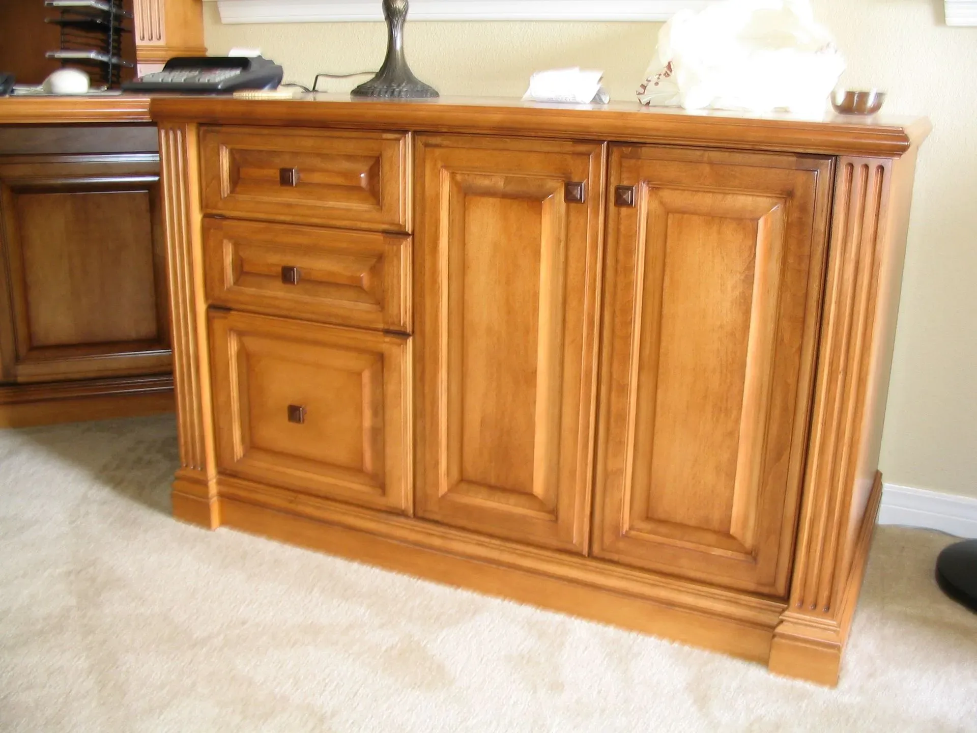 Wooden sideboard cabinet with drawers and paneled doors in a carpeted room