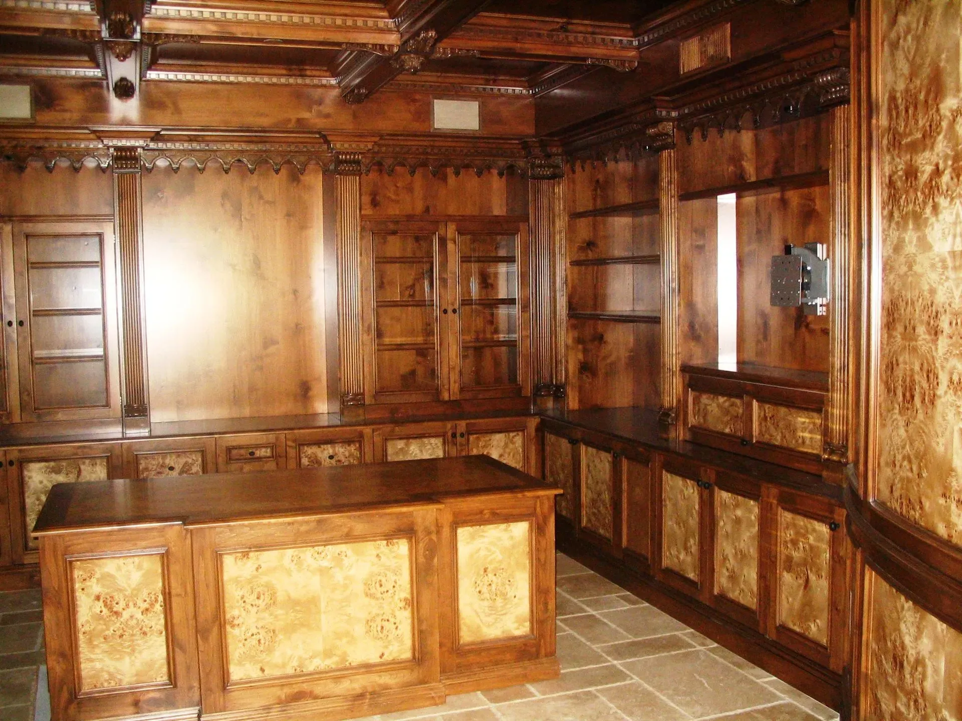 Wood-paneled room with ornate wood trim, tiled floor, and a large wooden desk at center