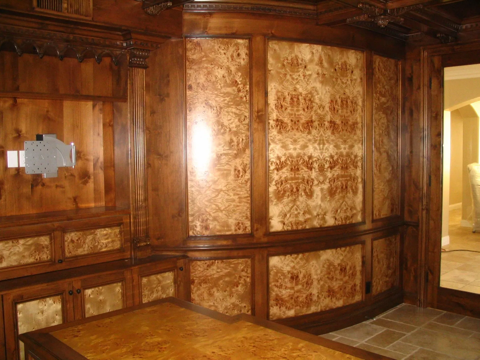 Ornate wooden-paneled room with built-in bench, curved wall, and stone floor under warm light