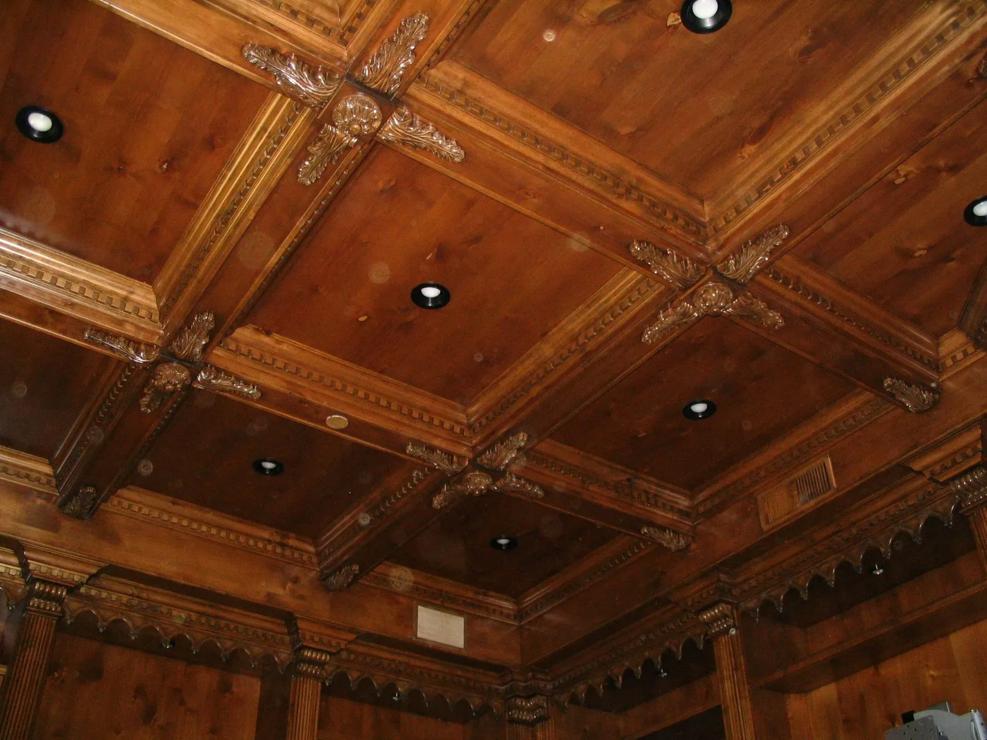 Ornate wood-paneled coffered ceiling with carved beams and recessed lights