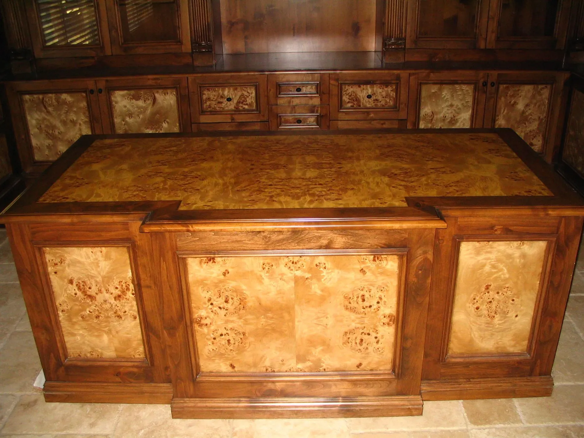 Ornate wooden desk with carved panels and a tan leather writing surface in a wood-paneled room