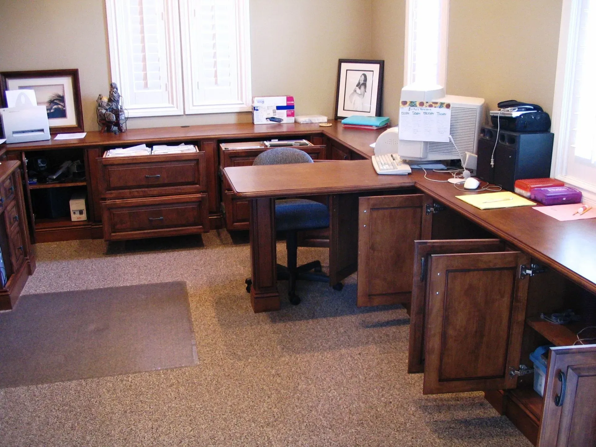Office with wooden desks, drawers, a computer printer, and a window in the back wall.