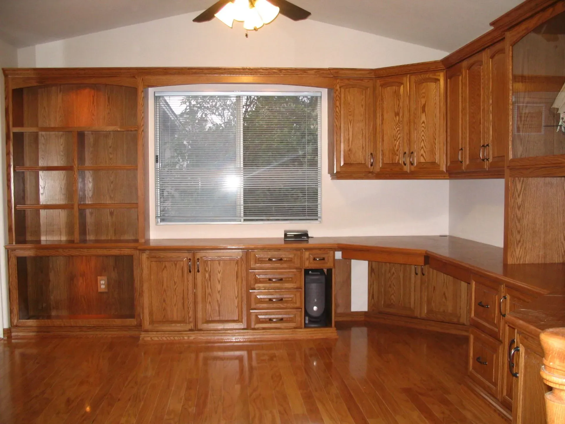 Wooden kitchen with cabinets, sink, and large window, empty and unfinished.