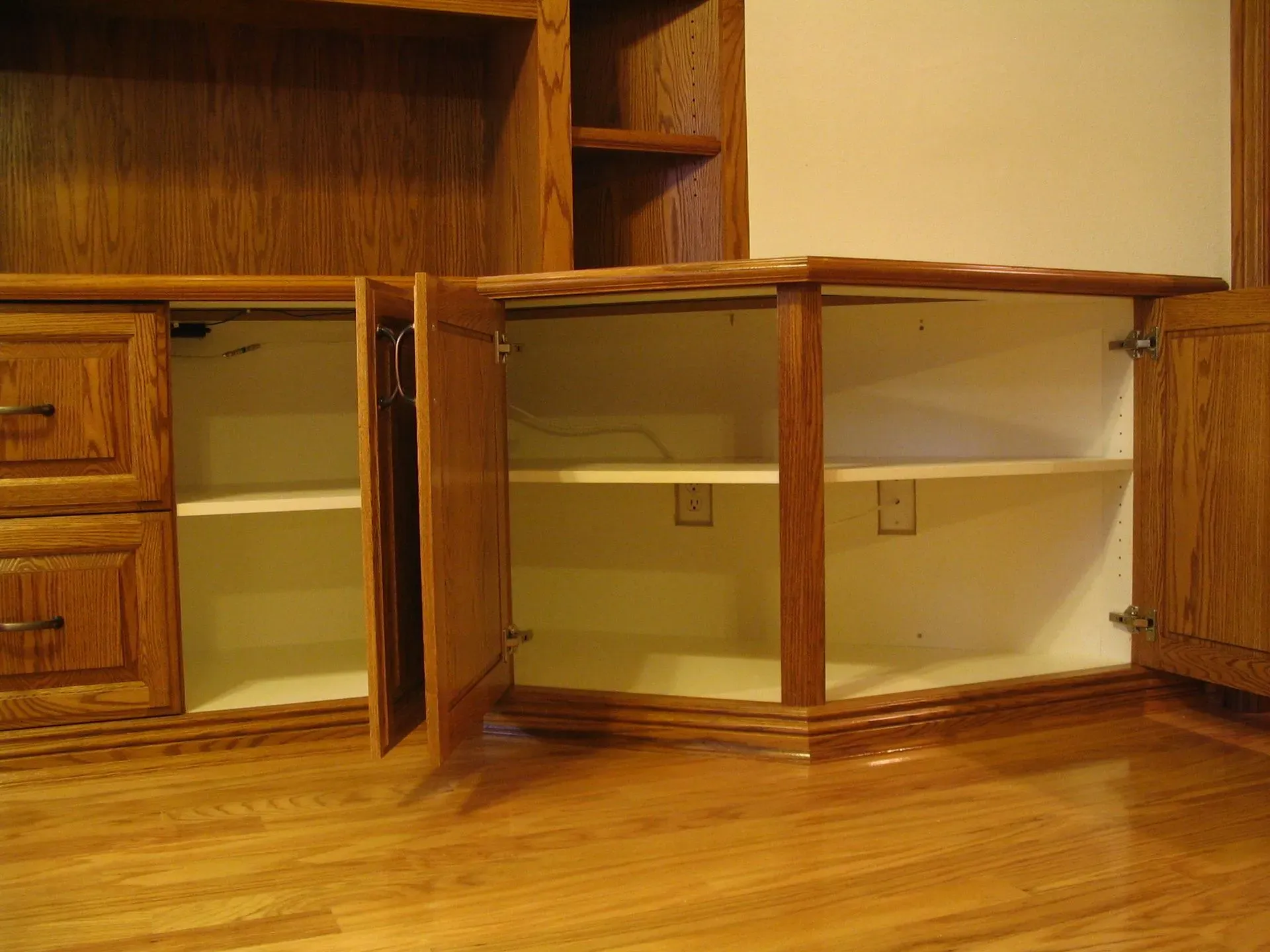 Wooden cabinets with open lower doors and empty shelves in a kitchen or office nook