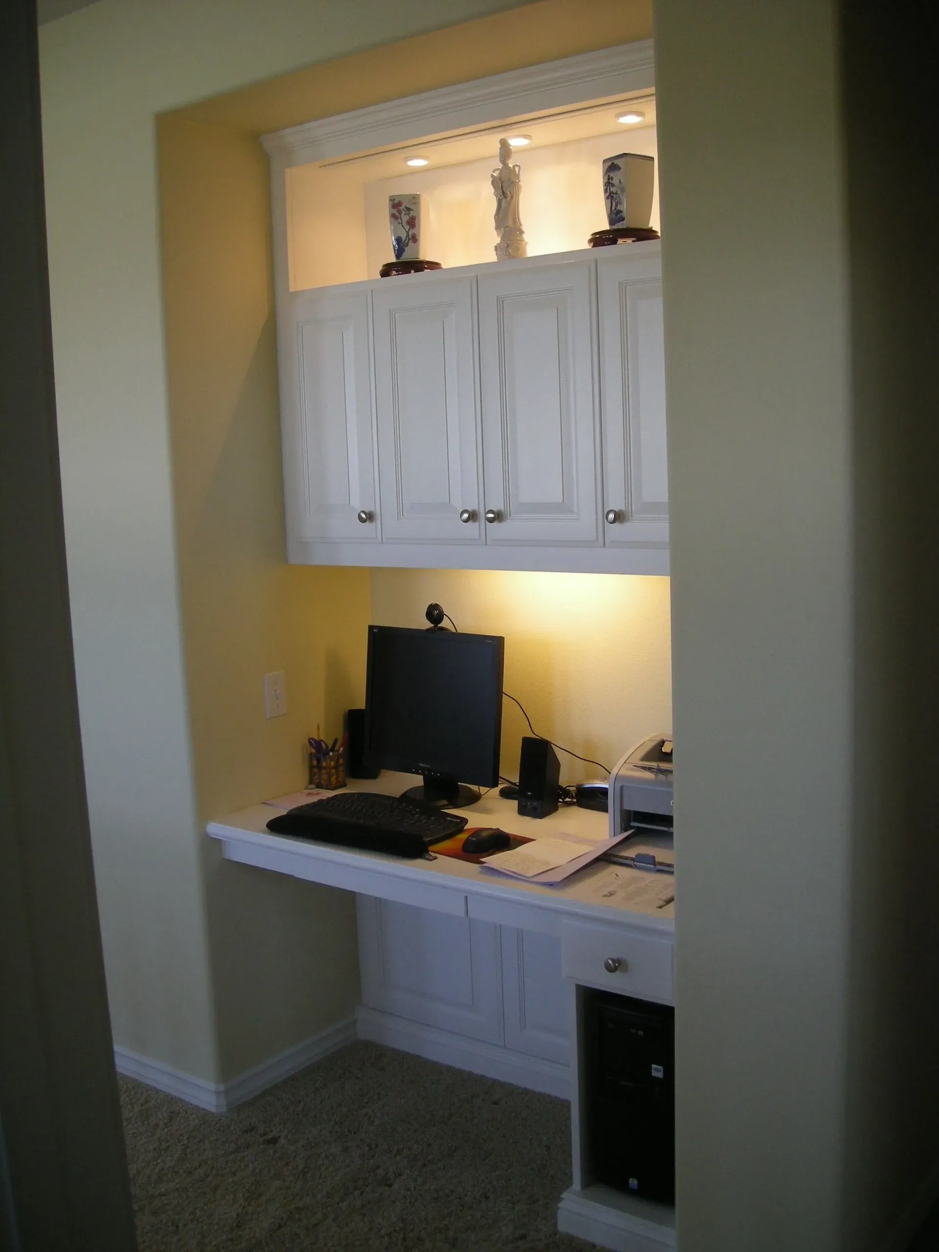 Built-in home office nook with desk, computer, cabinets, and warm under-cabinet lighting